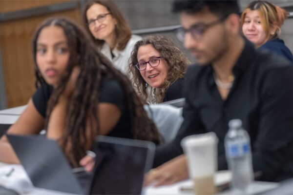 teacher crouching in a classroom where students are out of focus and she is in focus