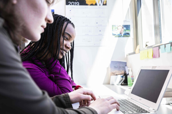 student working with mentor in an office looking at a computer screen together