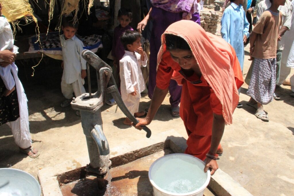 a lady getting water from a pump