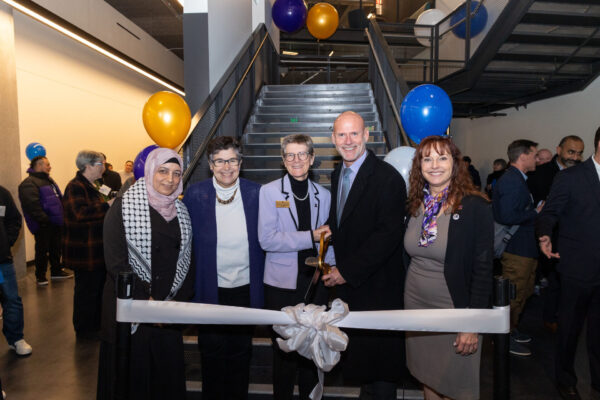 A group of people standing behind a ribbon.