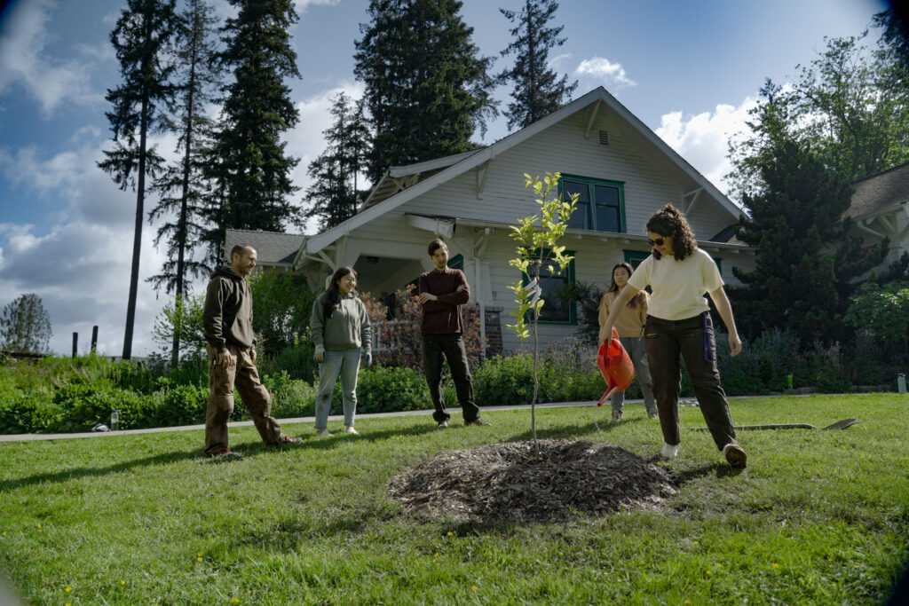 A person in a group waters a tree.