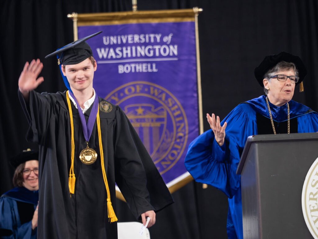 A person in a cap and gown wearing a medal standing next to another person at a podium.