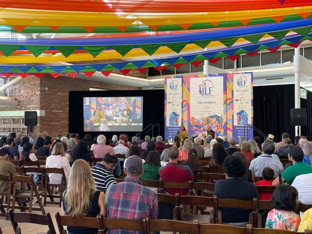 A group of people at an event watching a panel of speakers.