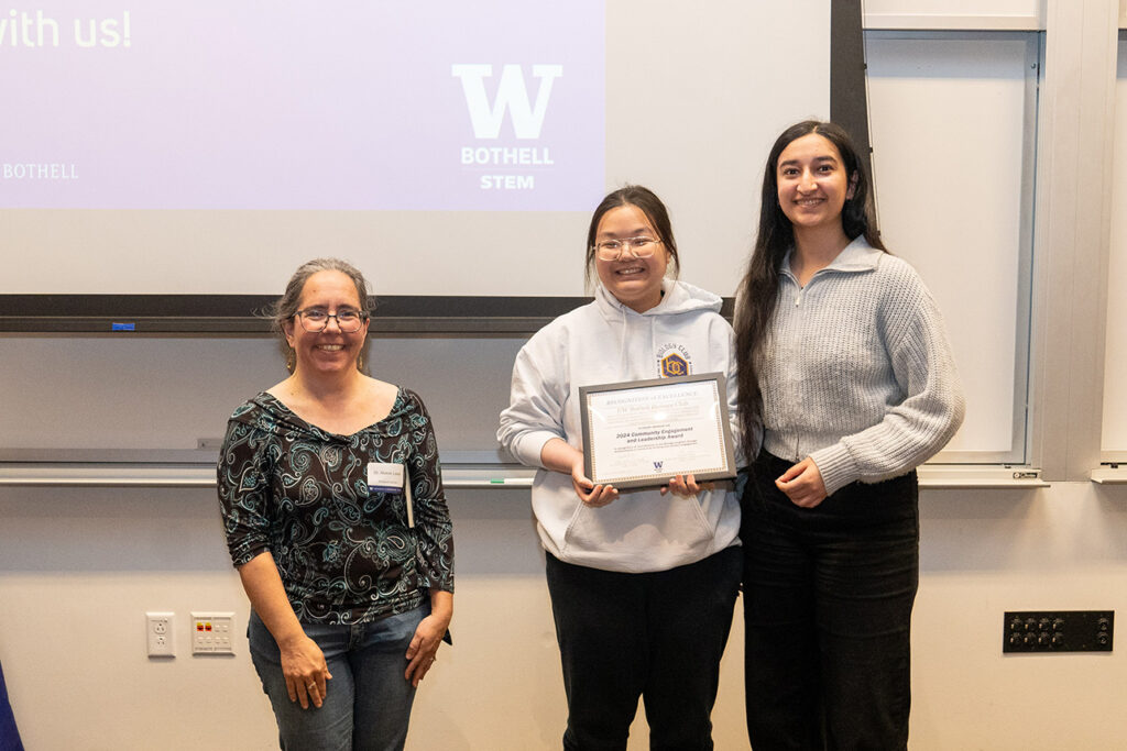 Biology division chair Alaron Lewis smiling with students who received their award. 