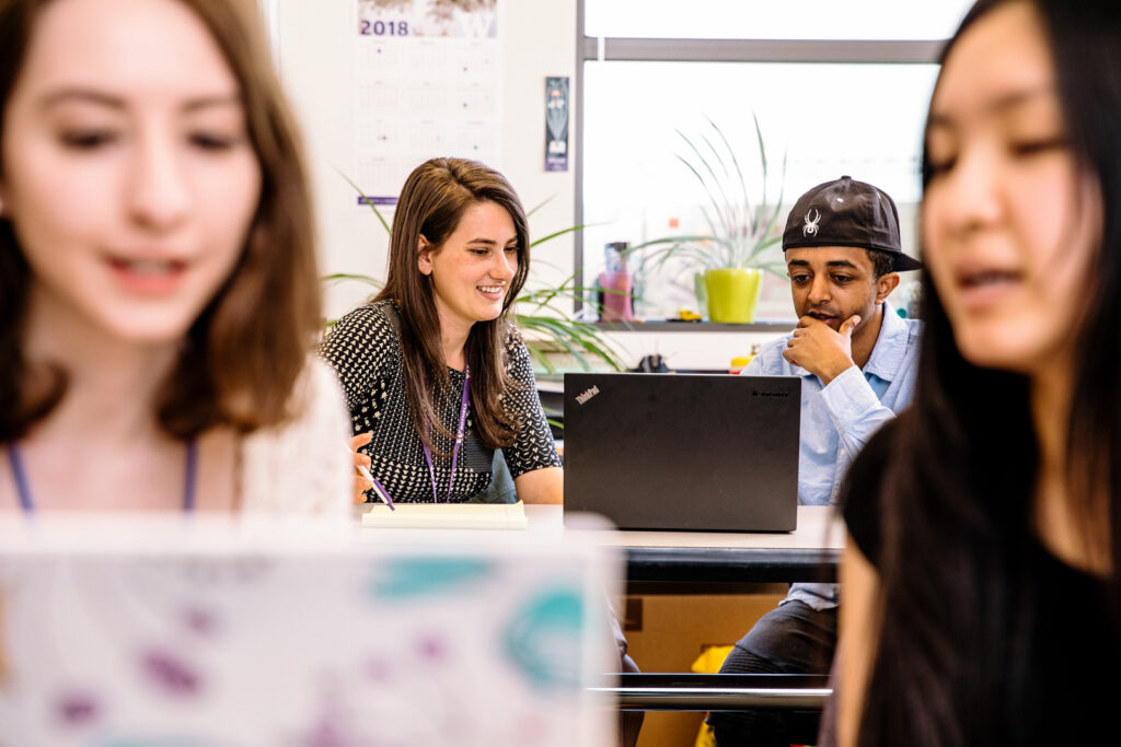 Two pairs of students, both looking at laptops. 