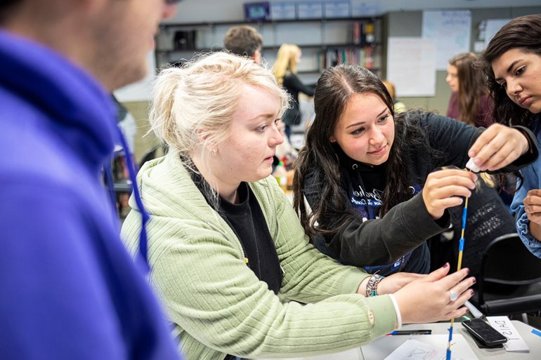 Students building spaghetti stick structure.