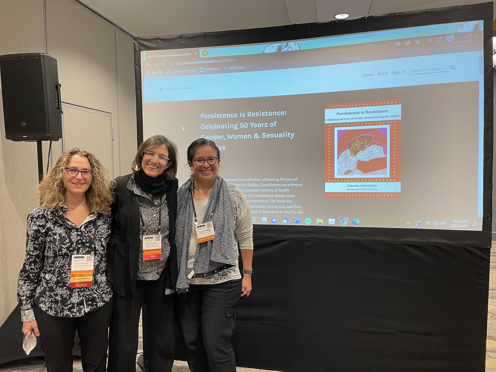 3 women standing together in front of Dr. Shayne's persistence is resistance presentation