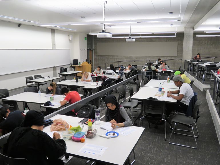 Zoha Awan, foreground, and others take exam at night.